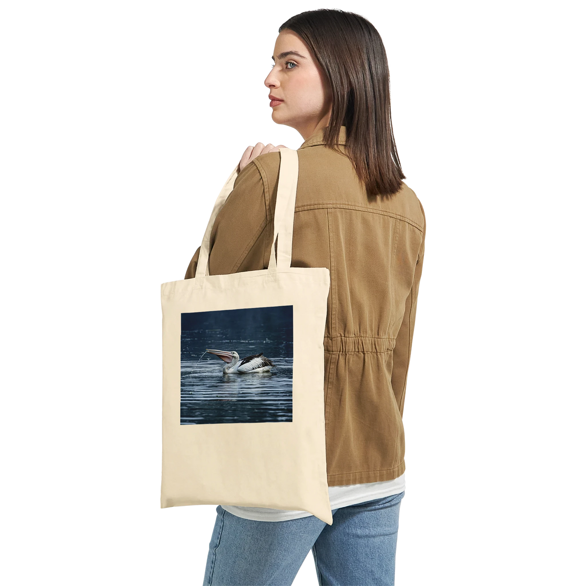 Woman carrying a natural canvas tote bag with a splashing pelican print over her shoulder