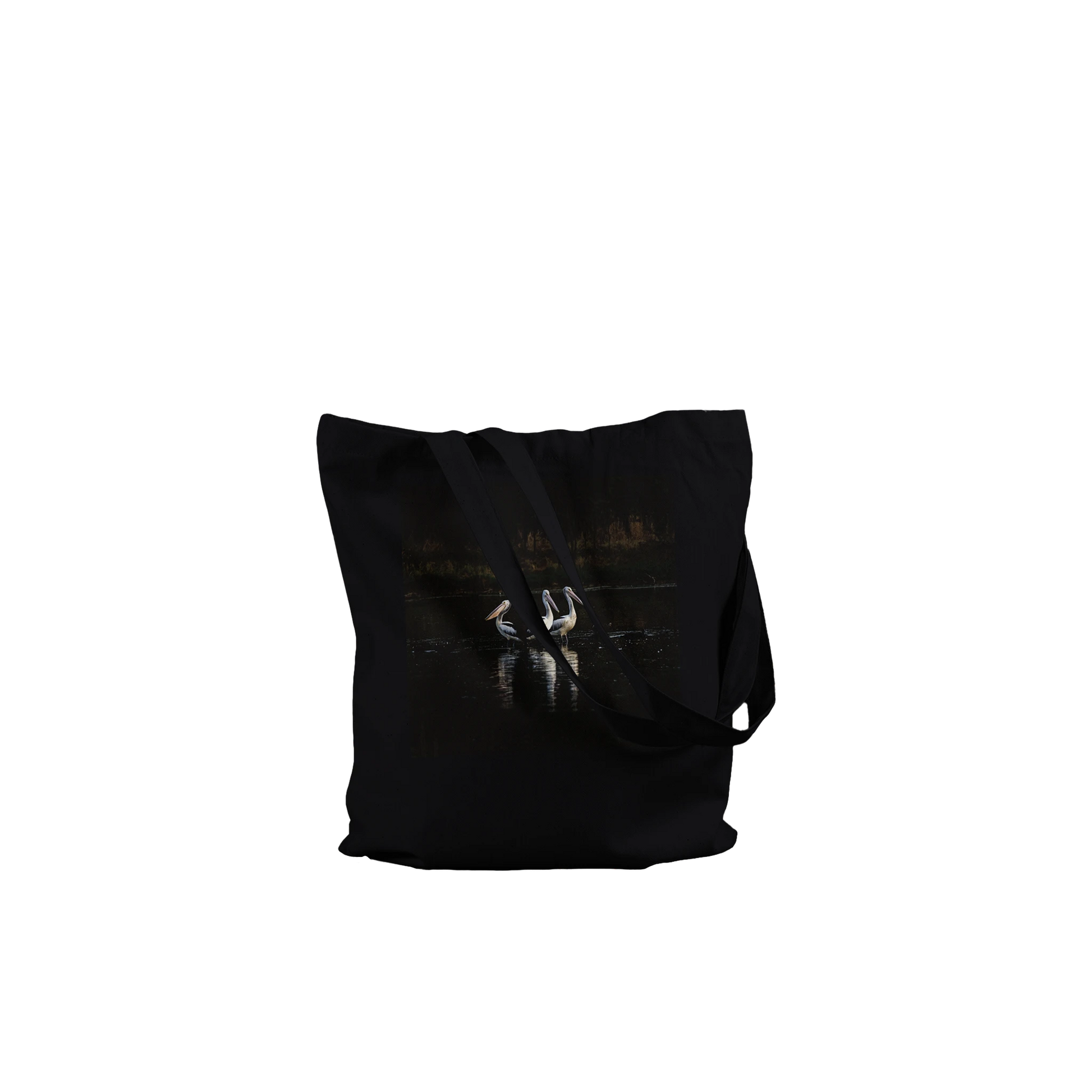 Three Pelicans canvas tote bag, black, front view laid flat with straps draped — fine art photograph of three pelicans standing together in still water at dusk