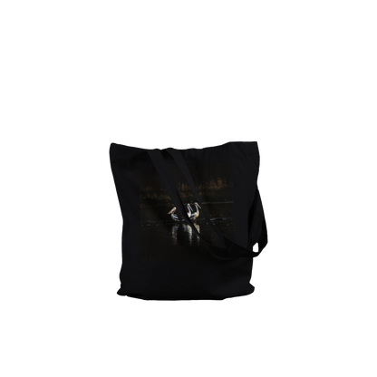 Three Pelicans canvas tote bag, black, front view laid flat with straps draped — fine art photograph of three pelicans standing together in still water at dusk