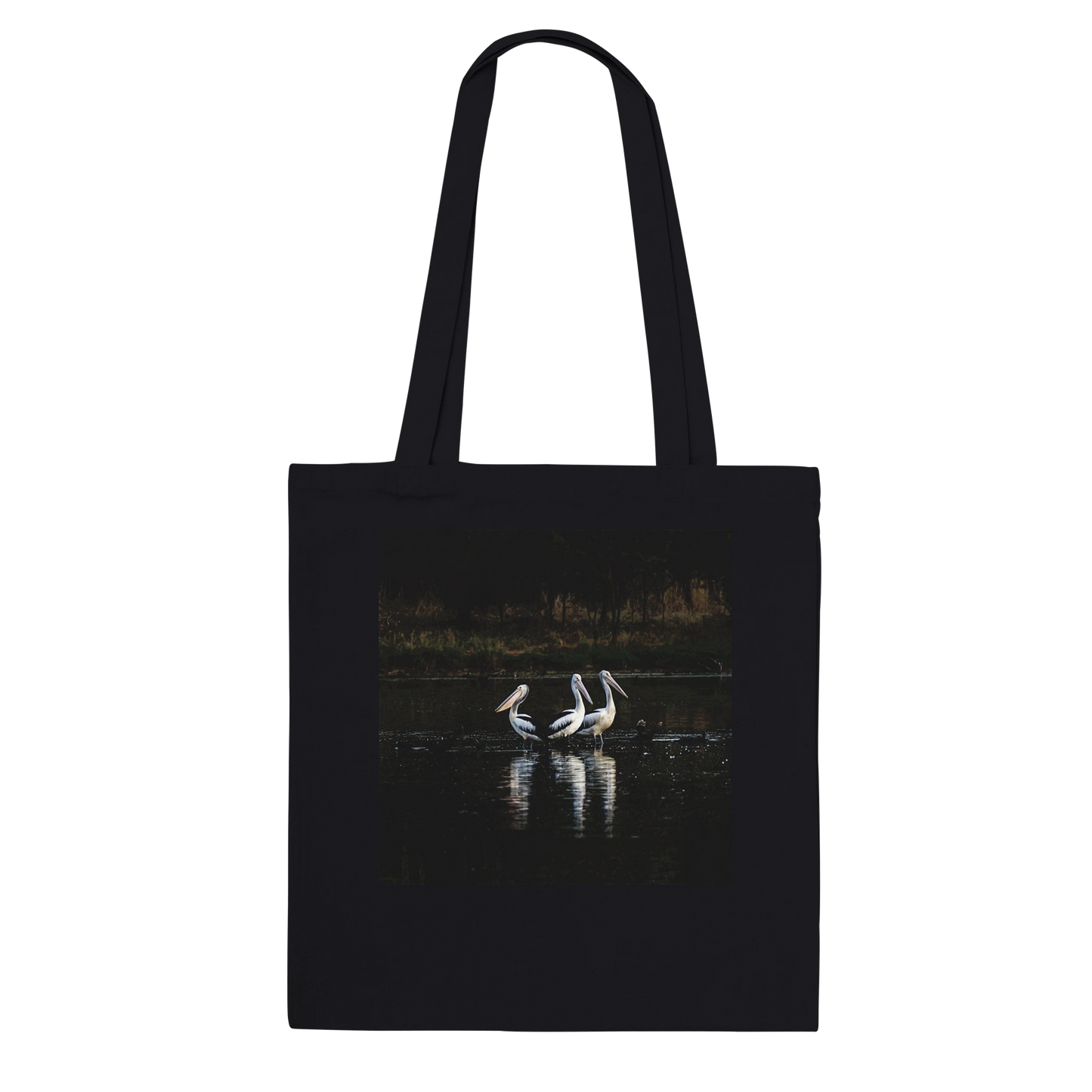 Three Pelicans canvas tote bag, black, hanging front view — fine art photograph of three pelicans standing together in still water at dusk
