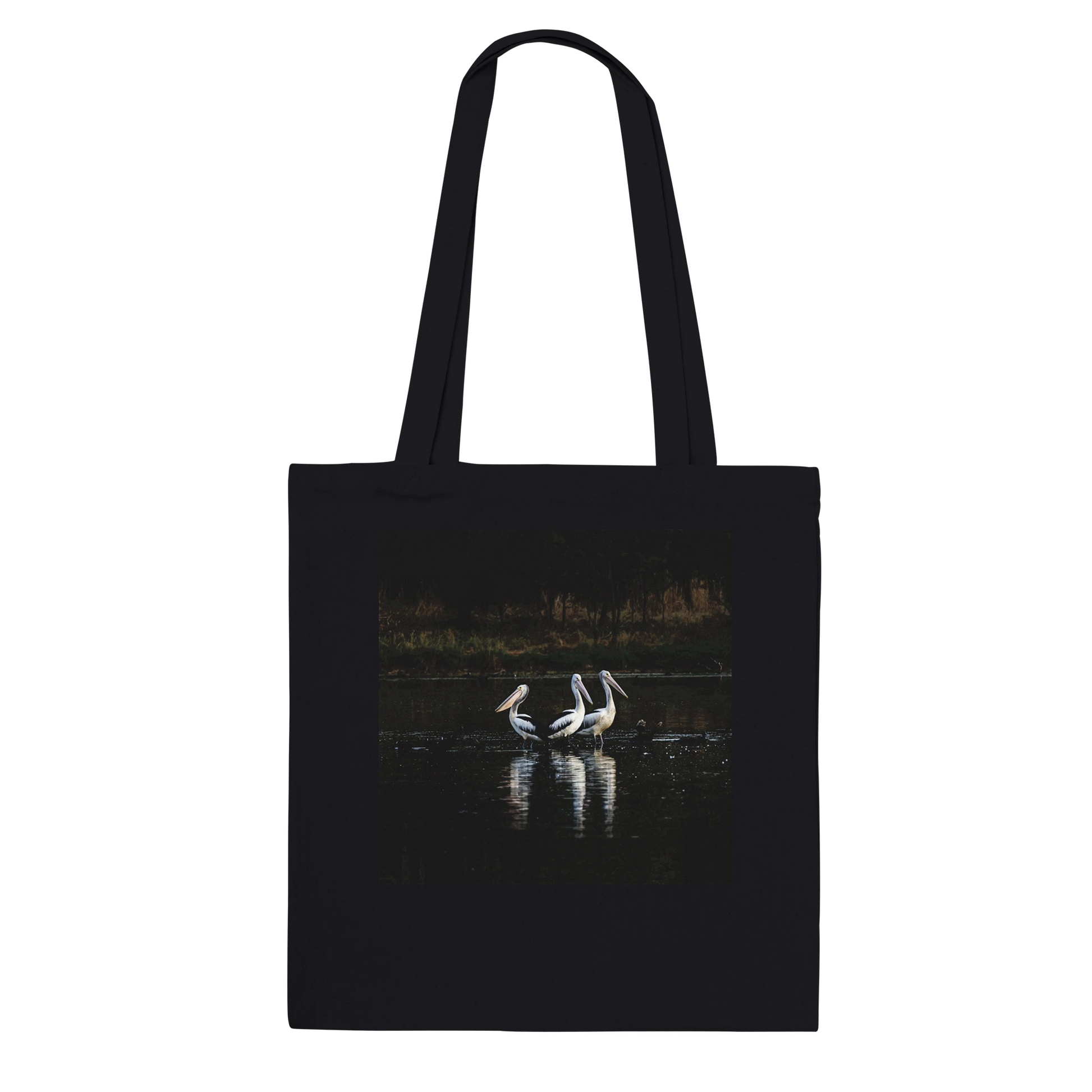 Three Pelicans canvas tote bag, black, hanging front view — fine art photograph of three pelicans standing together in still water at dusk