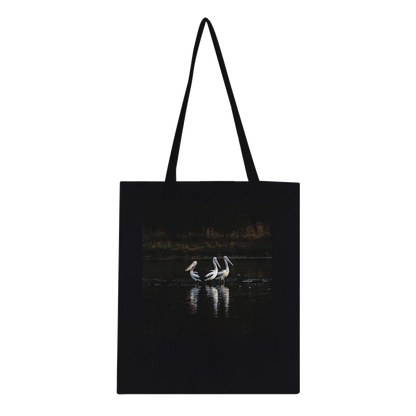 Three Pelicans canvas tote bag, Classic Black, front — fine art photograph of three pelicans standing together in still water at dusk