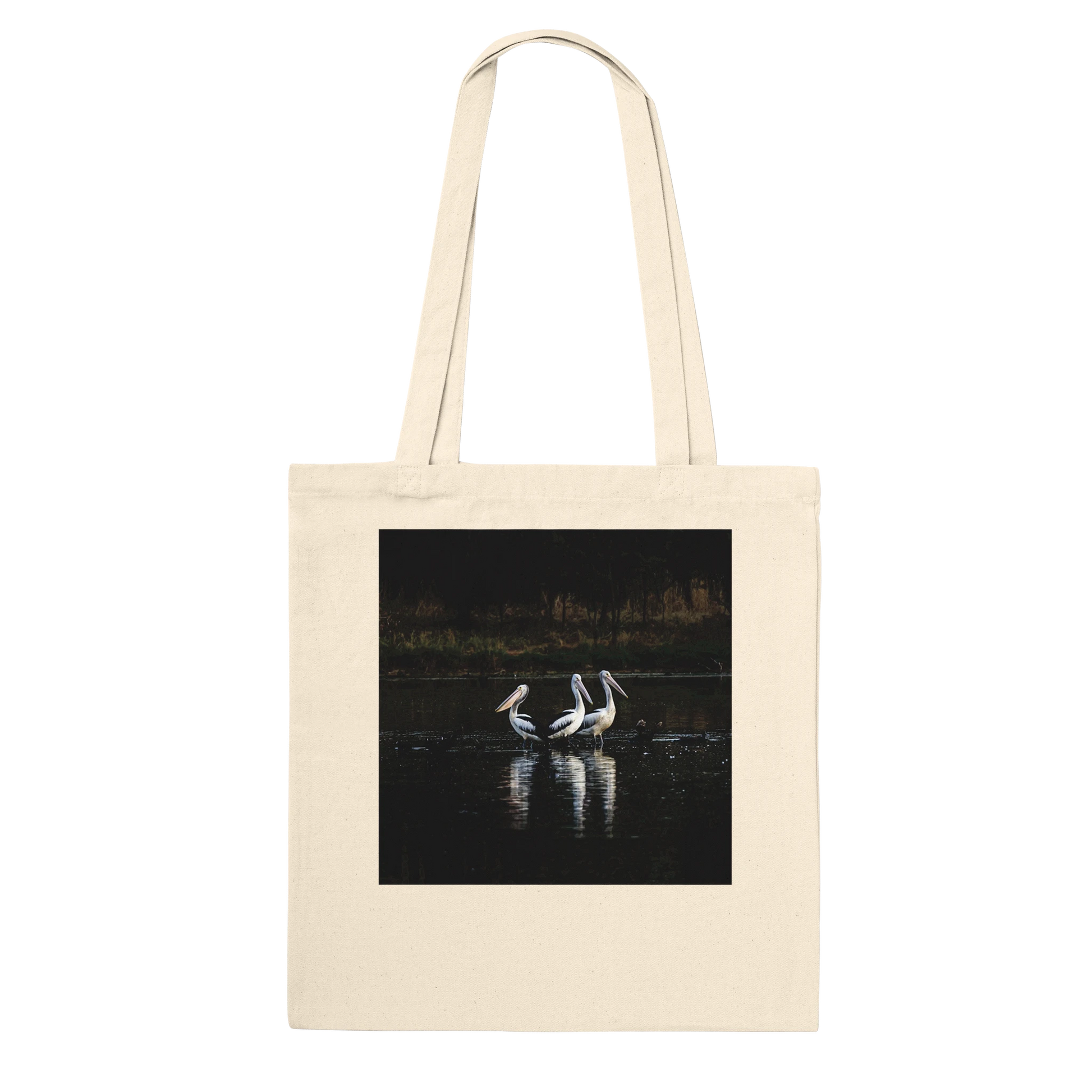 Three Pelicans canvas tote bag, natural, hanging front view close-up — fine art photograph of three pelicans standing together in still water at dusk