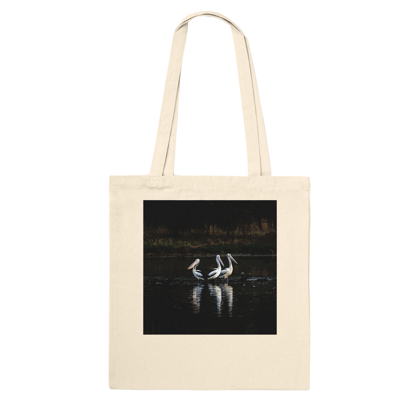 Three Pelicans canvas tote bag, natural, hanging front view — fine art photograph of three pelicans standing together in still water at dusk