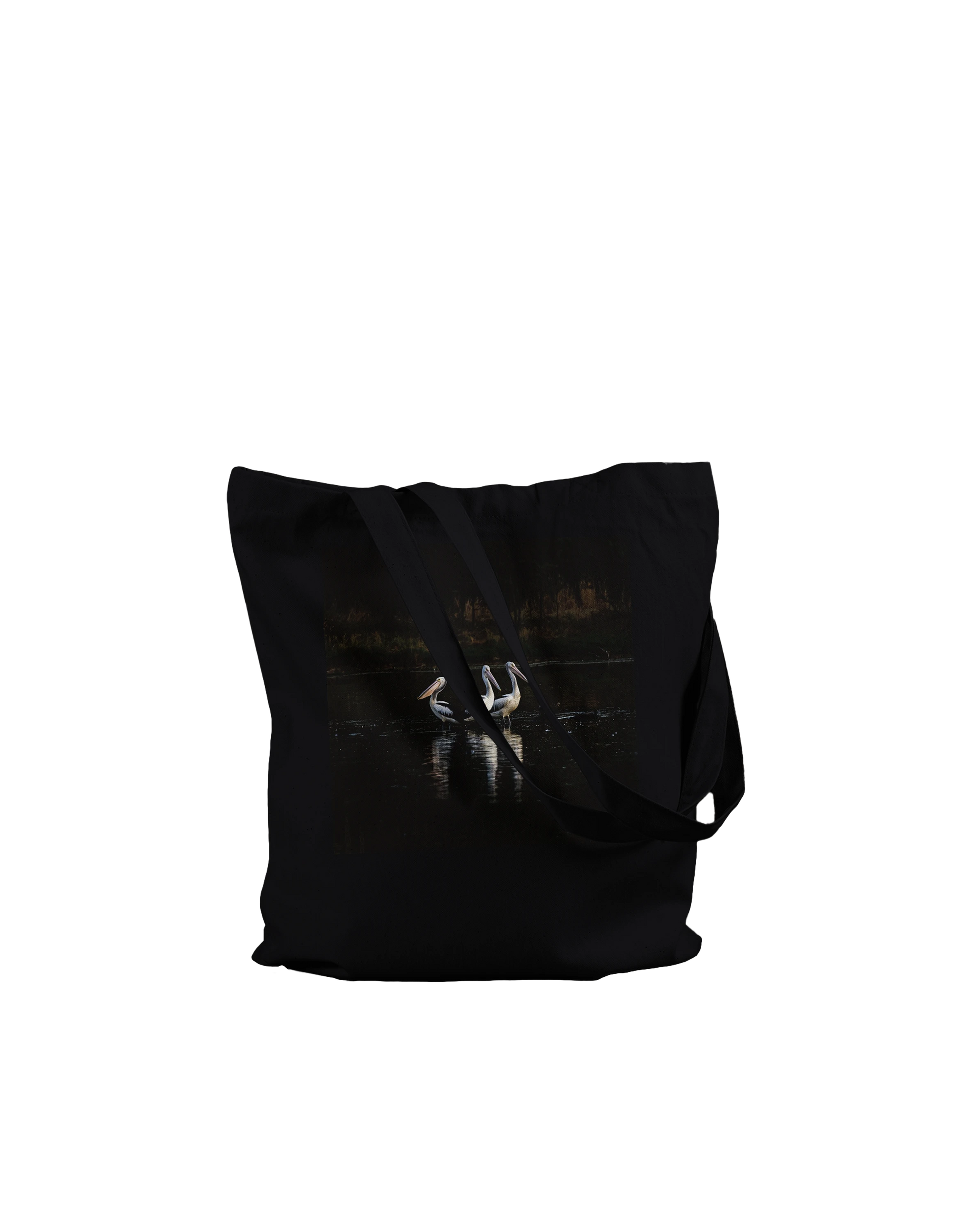 Three Pelicans canvas tote bag, Premium Black, on-ground front view — fine art photograph of three pelicans standing together in still water at dusk